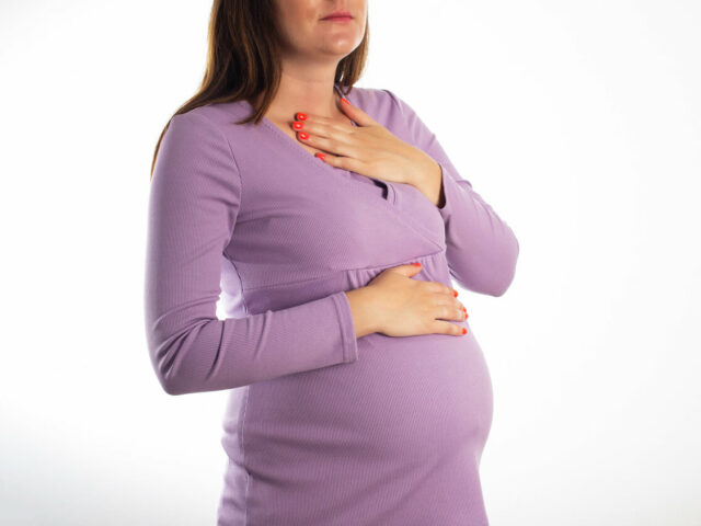 Ibu hamil memegang dada dan perut atas karena rasa tidak nyaman saat hamil.