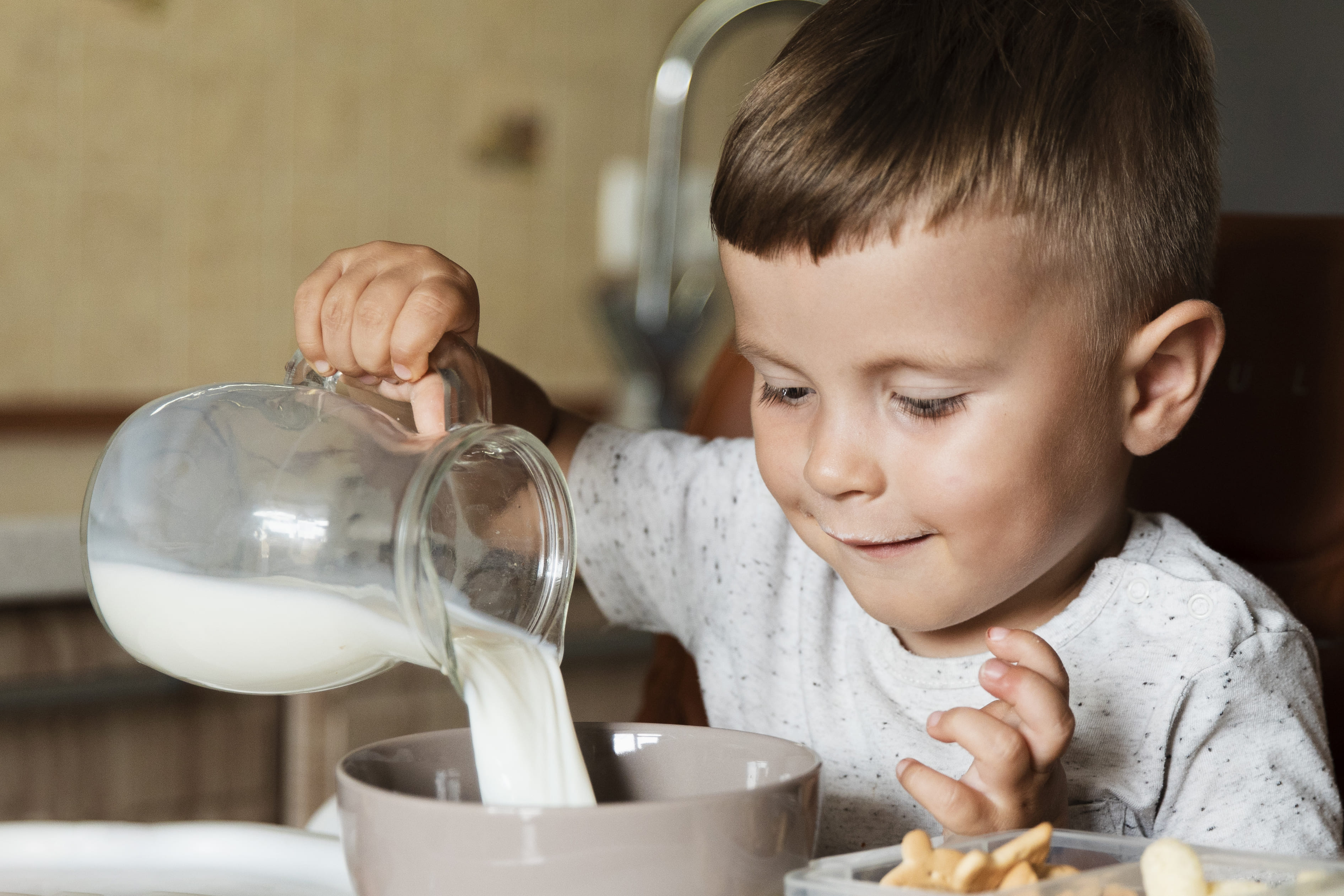 Anak menuang susu dari satu wadah ke wadah lain